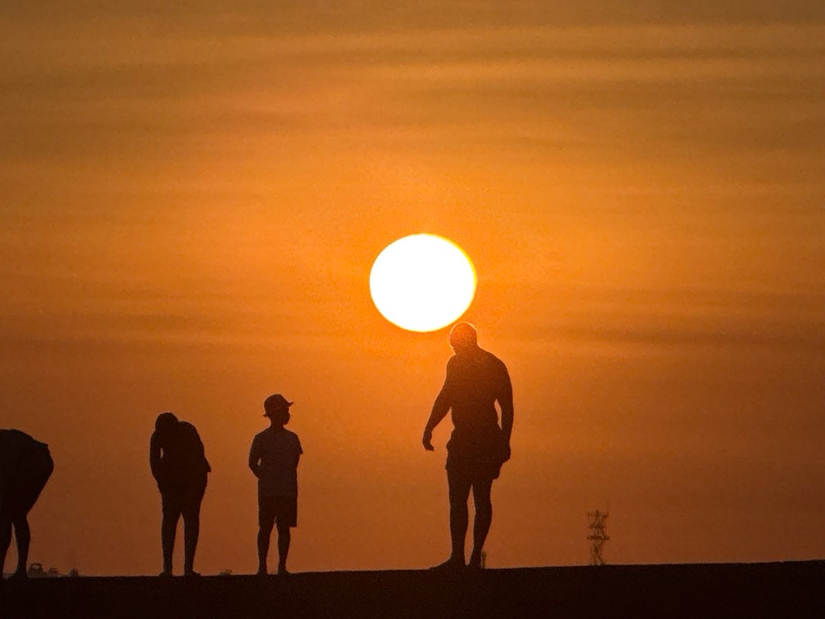 Golden hour at the waterfront: waves, sailboats, and sunset silhouettes