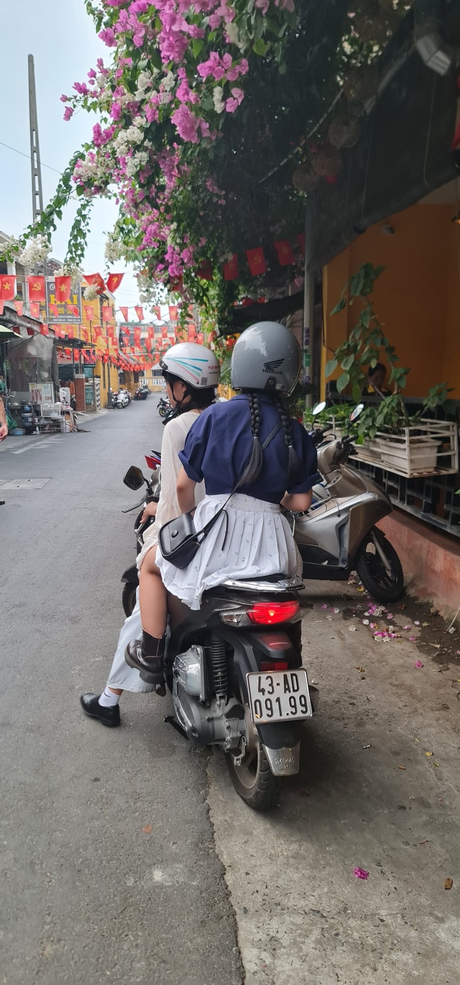 Motorcycle riders travel through flag-decorated street in Hội An