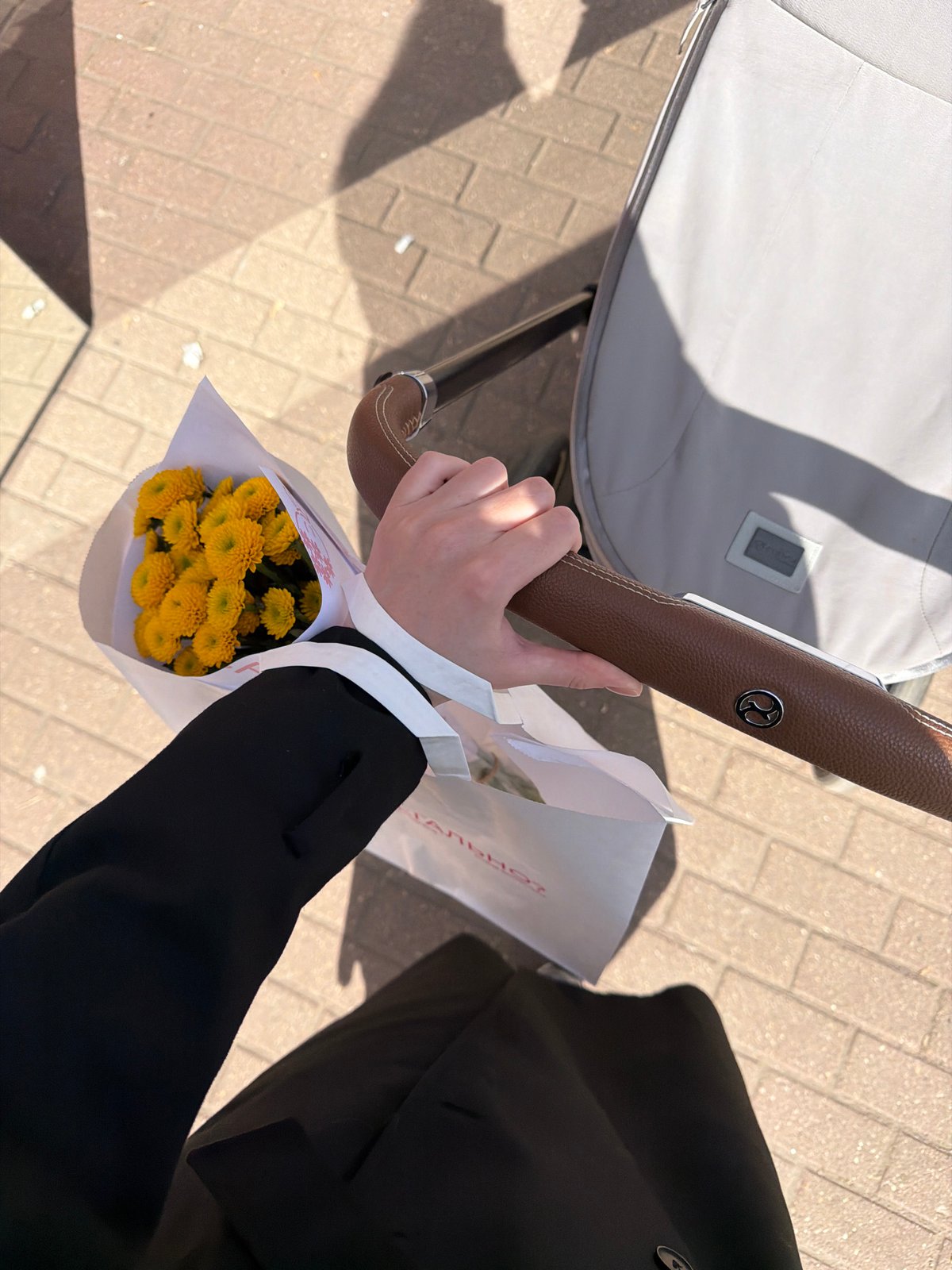 Parent with stroller carries yellow flowers in Khimki