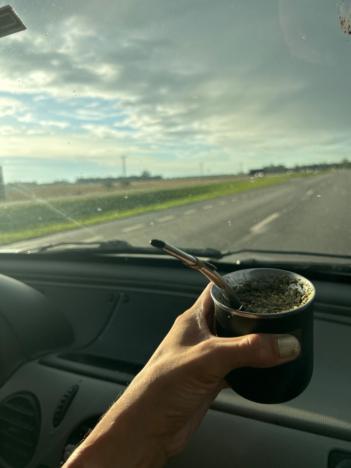 Traveler drinks traditional mate while driving through Argentine countryside