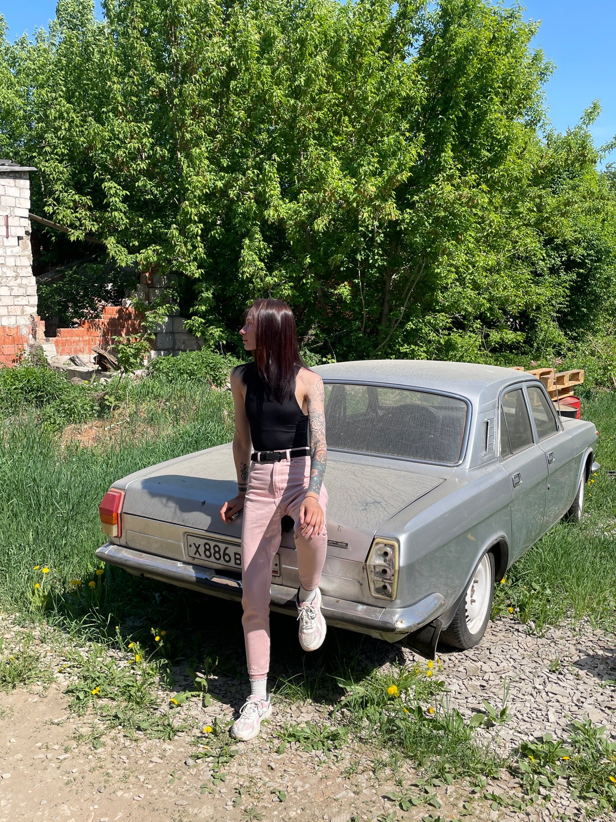 Woman leans against dirty silver car in Chemoshur