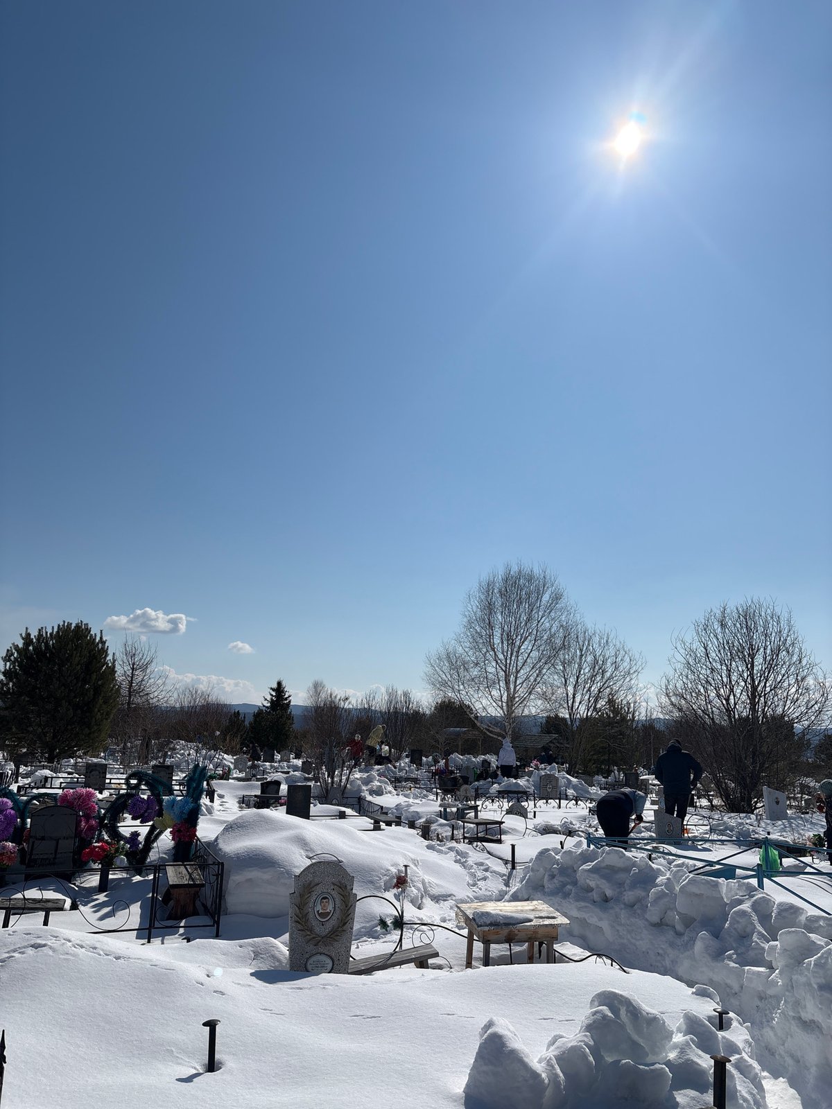 Snow blankets cemetery in Невон, Russia under clear skies