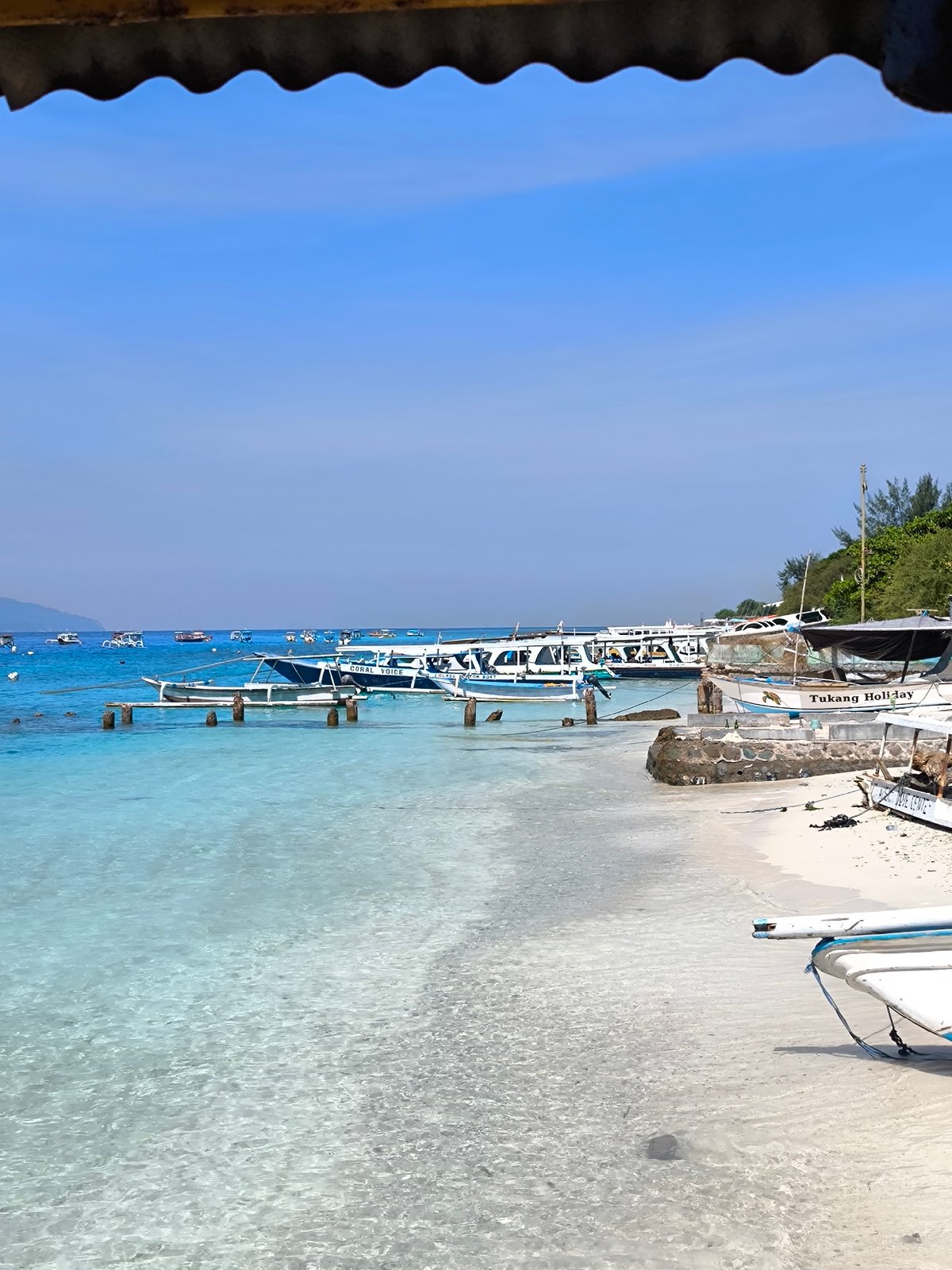 Peaceful Indonesian beach scene captured with boats visible offshore