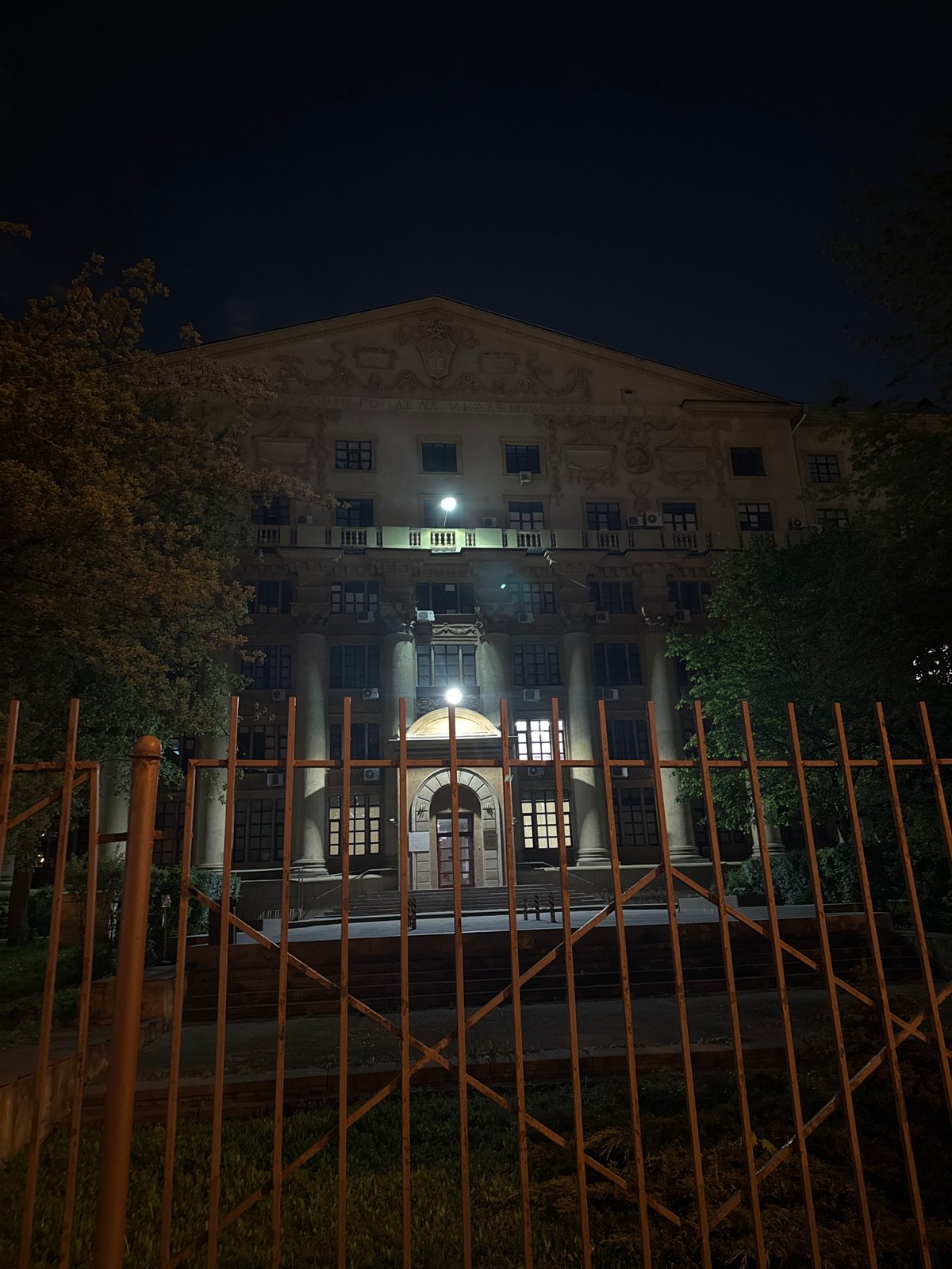 Man poses with outstretched arms near gated Moscow building