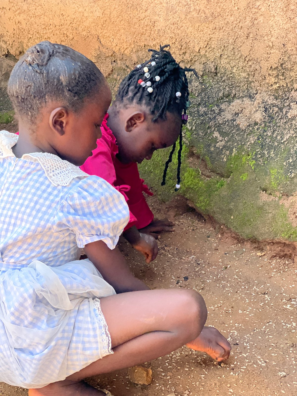 Kids gathered outdoors in Jos, busy around pots and basins