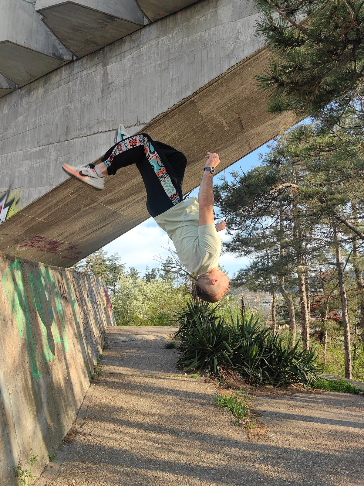 Man performs upside-down parkour move under concrete bridge
