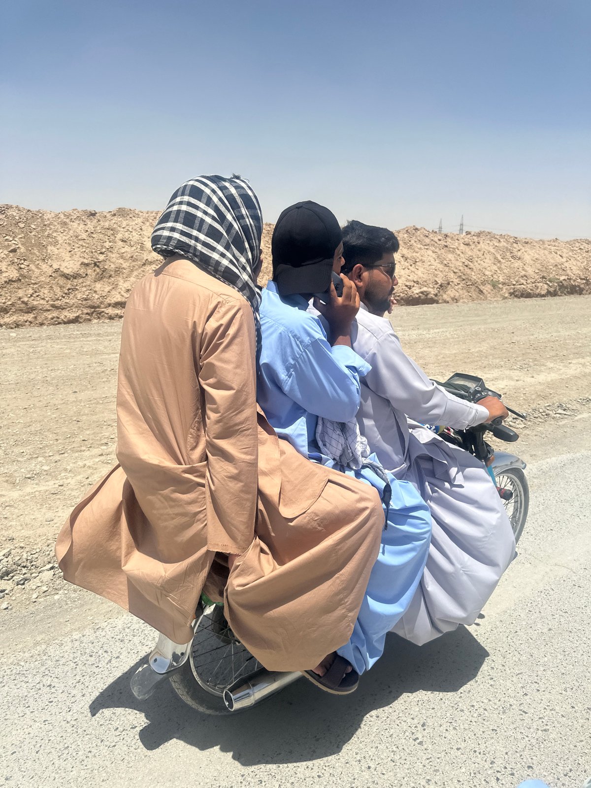 Three men rest roadside in Yaru Karez, Pakistan