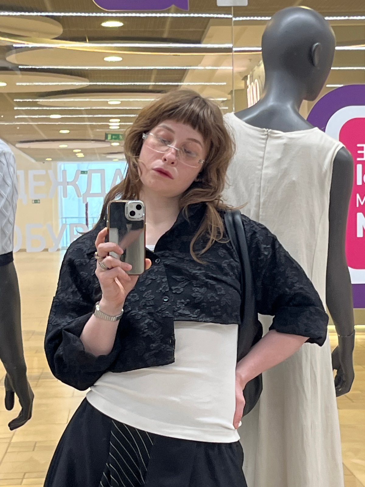 Mirror selfies in a Moscow clothing store, mid-outfit decision