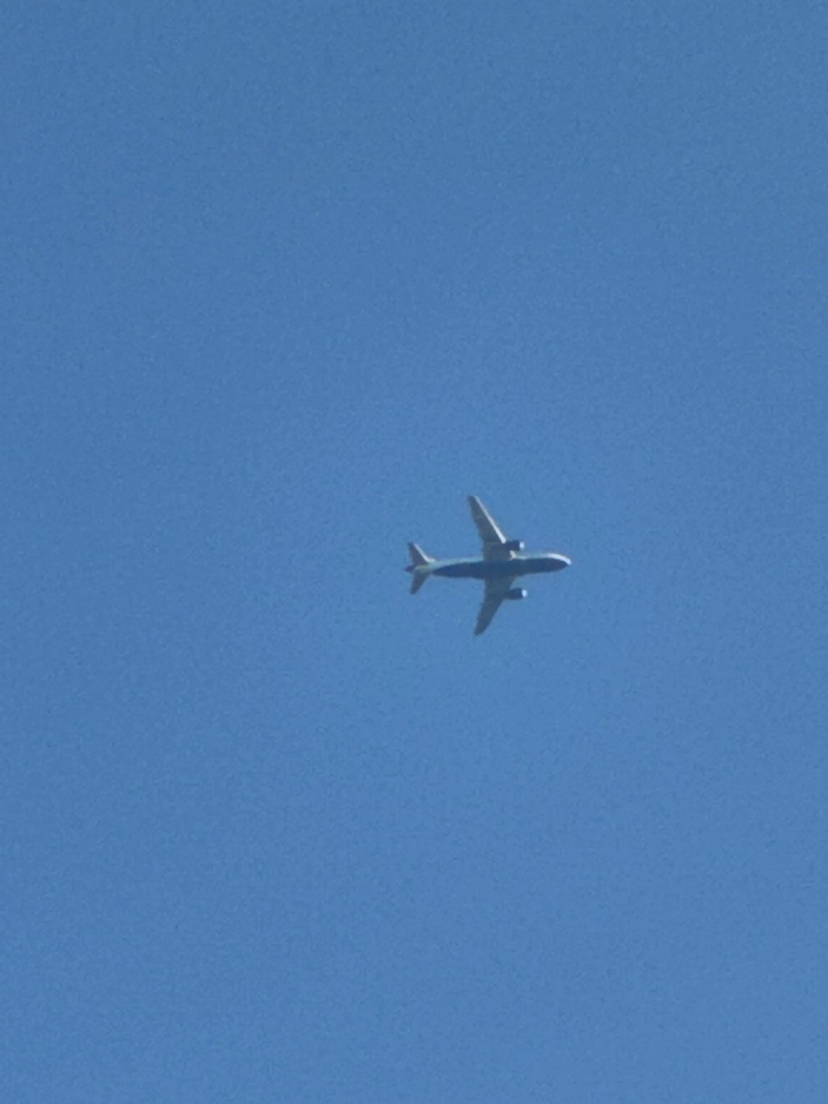 Orange-accented commercial jet cruises through clear London skies