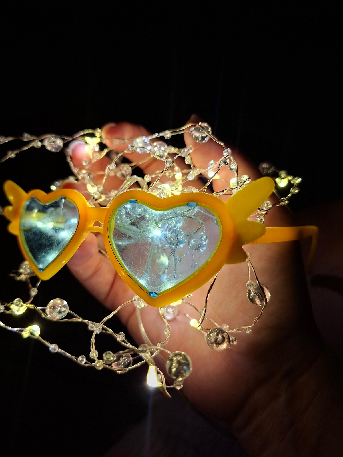 Fairy lights and heart sunglasses in a dim indoor setting