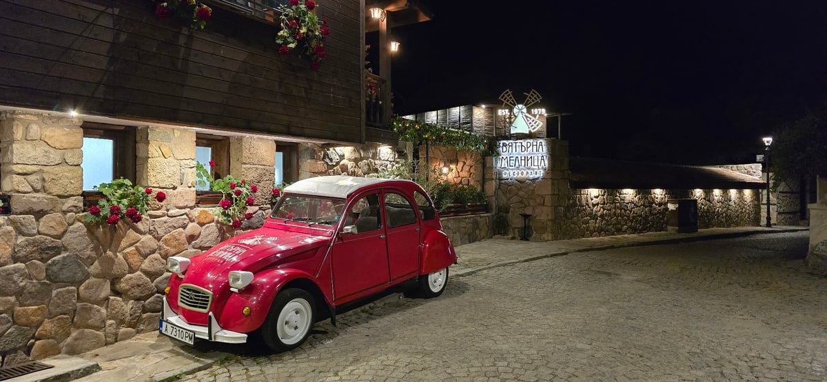 Red 2CV parked on cobblestones outside a flower-lined Sozopol building