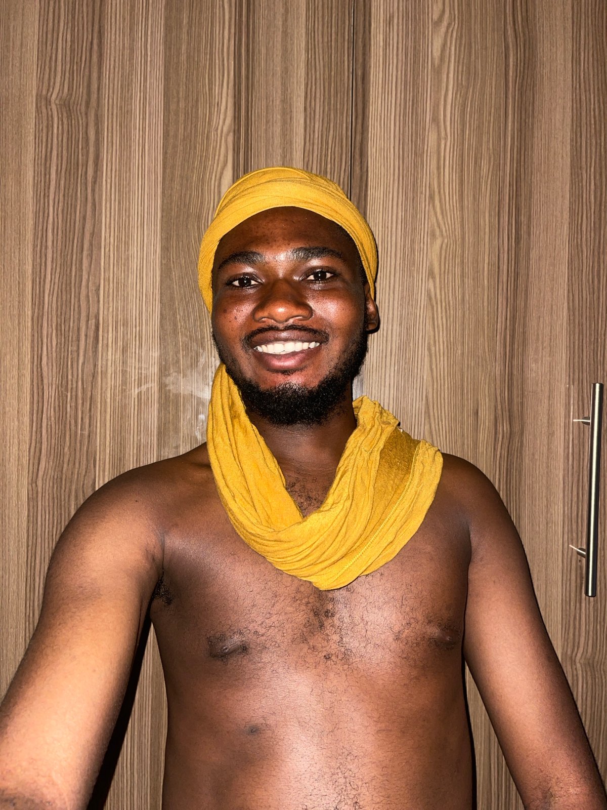 Man in yellow head wrap rests indoors in Muchiya