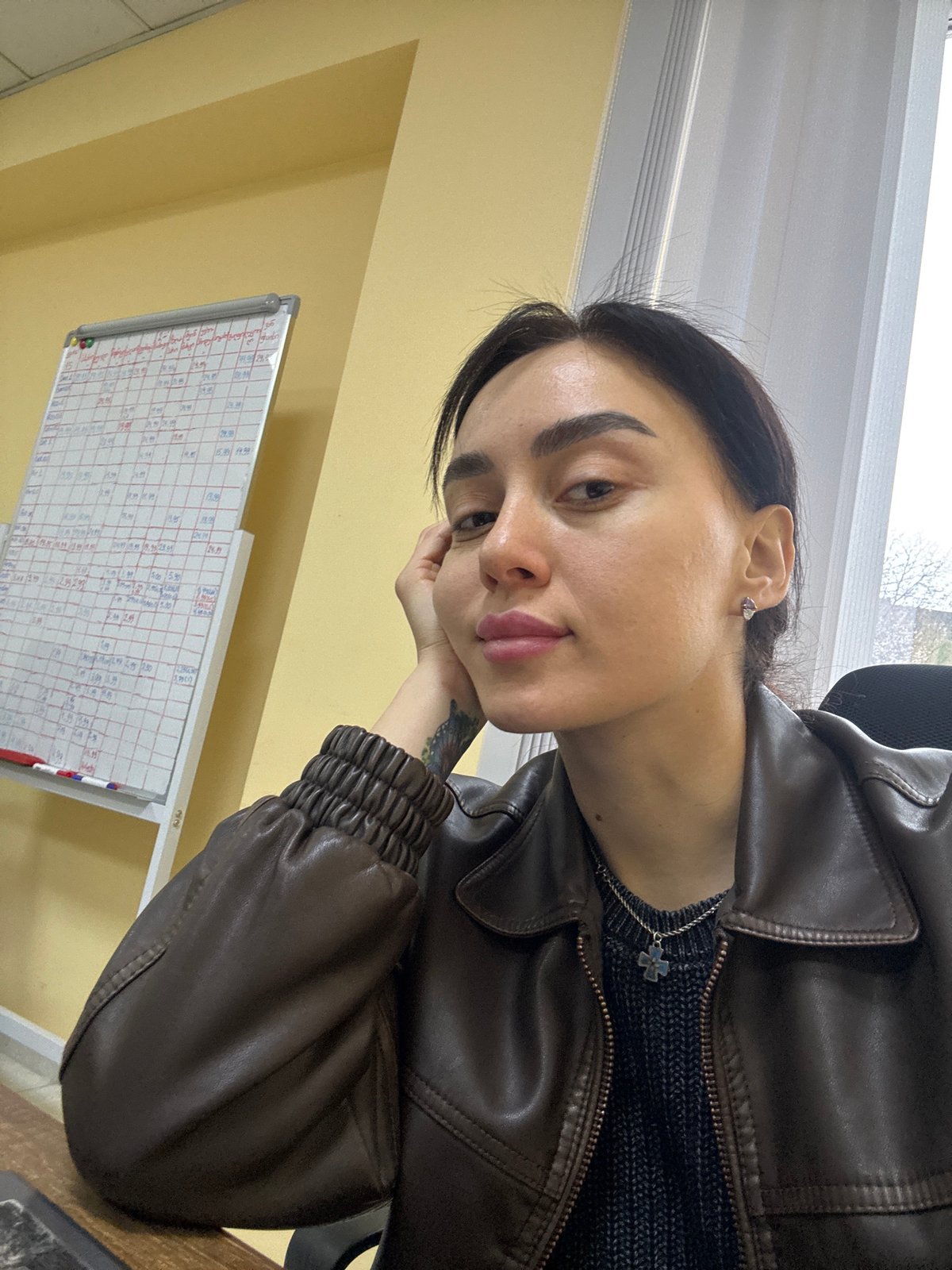 Person in leather jacket sits by office window in Tbilisi