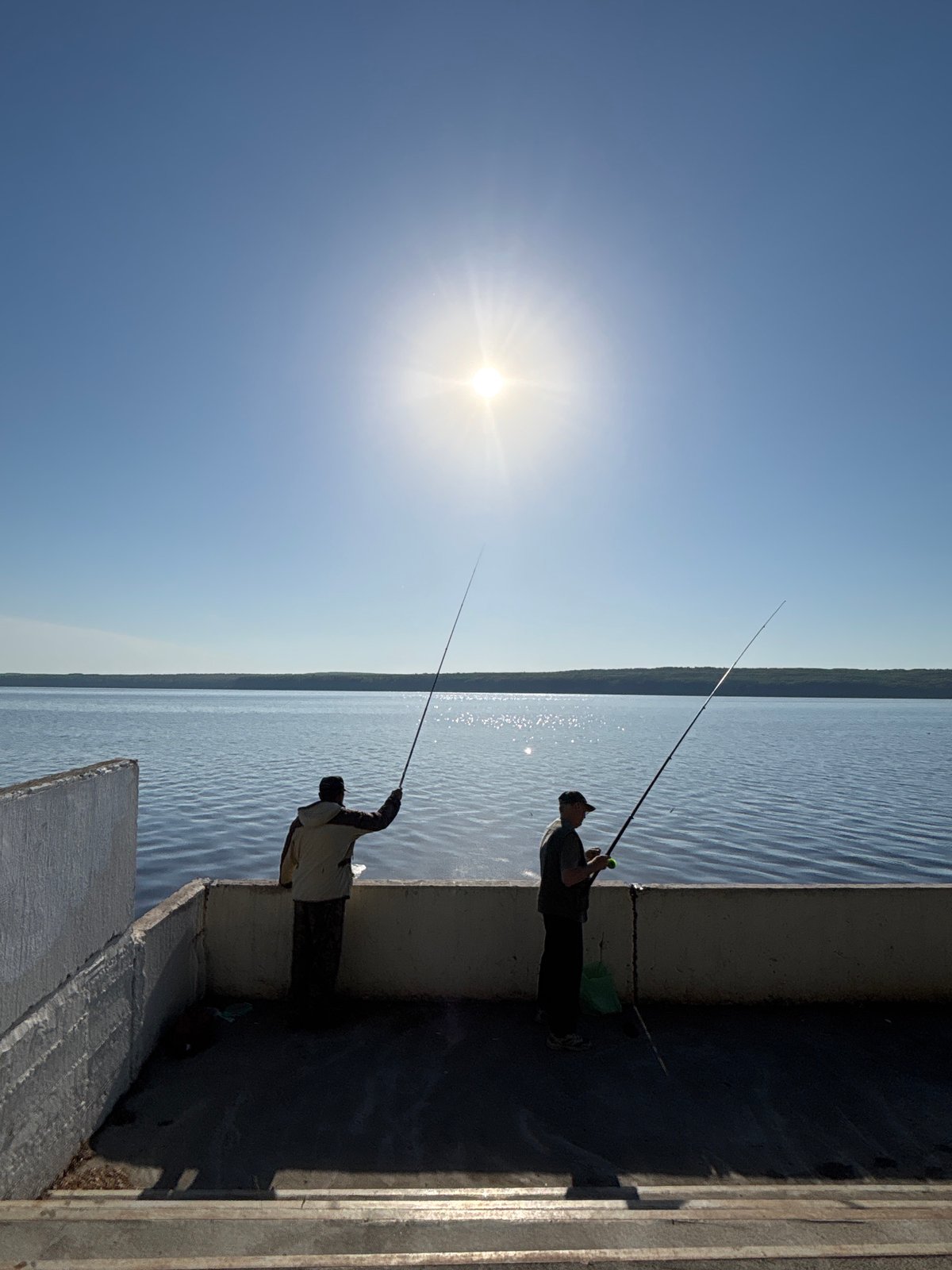 Two men fish from pier in Chaikovsky, Russia
