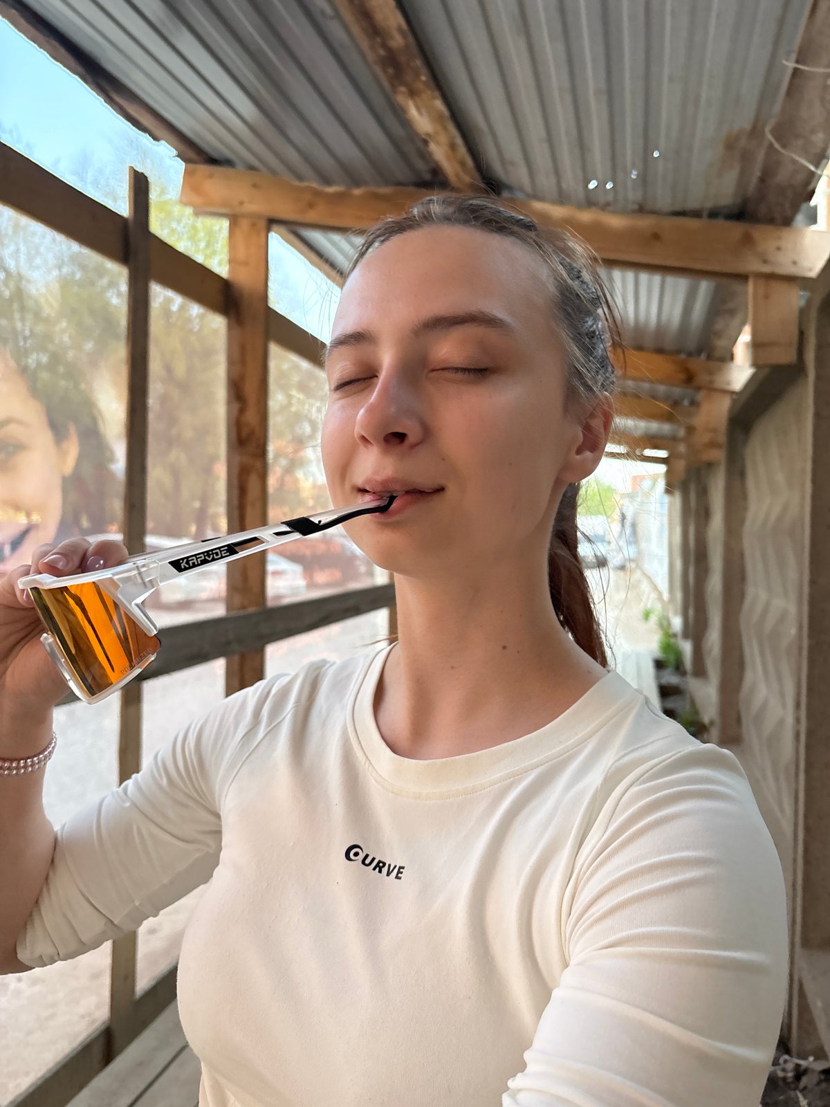 Woman holds orange sunglasses in mouth indoors in Perm