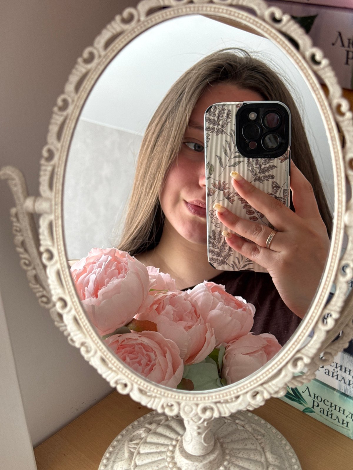 Woman takes mirror selfies with ornate oval mirror indoors