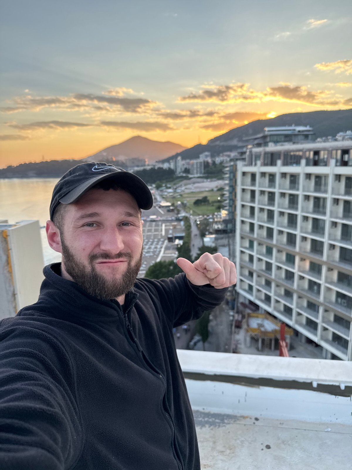 Man gives thumbs-down from rooftop during city sunset