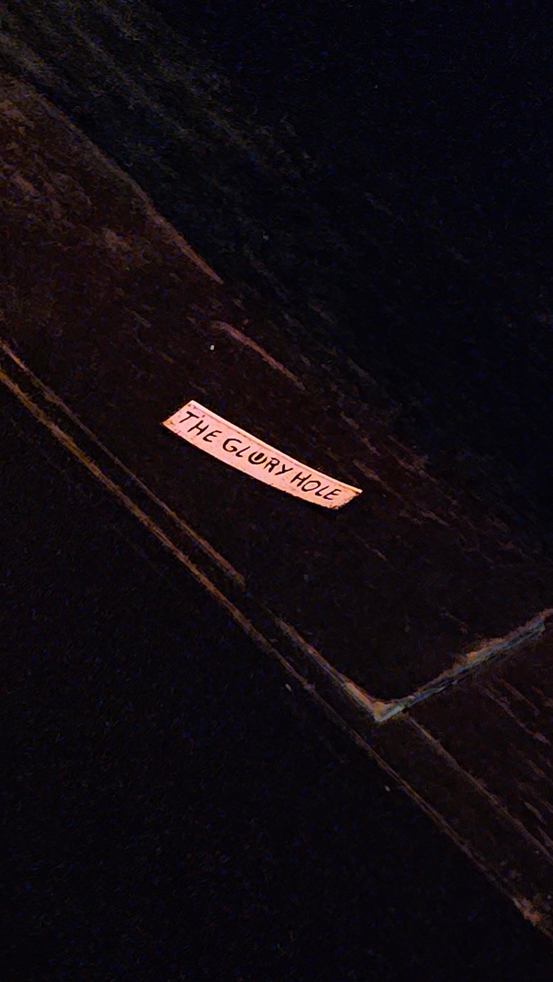 Wooden sign reading "The Glory Hole" photographed in Buenos Aires