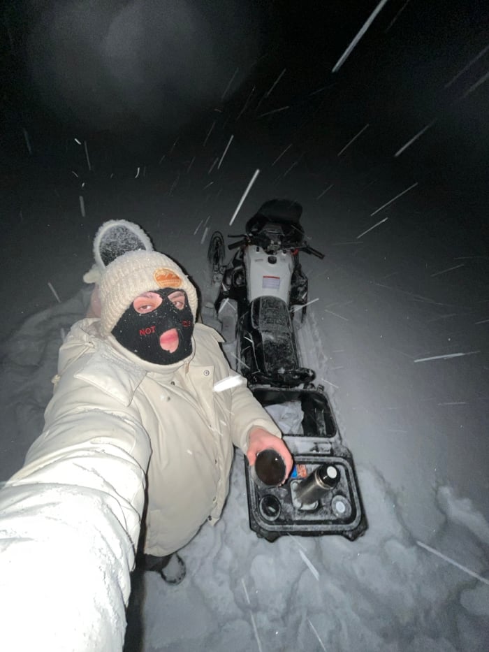 Winter traveler with motorcycle pauses during heavy snowfall in Russia