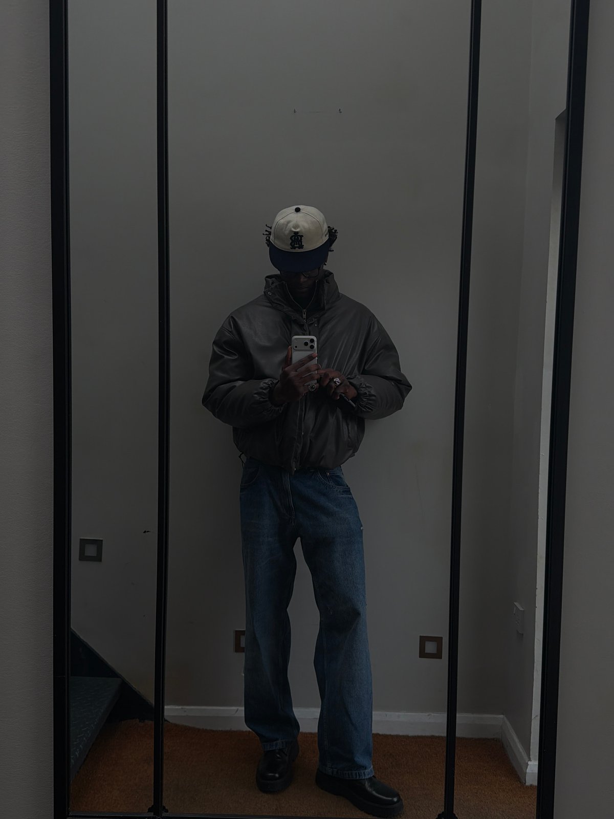 Person in layered winter clothing reflected in mirror, London