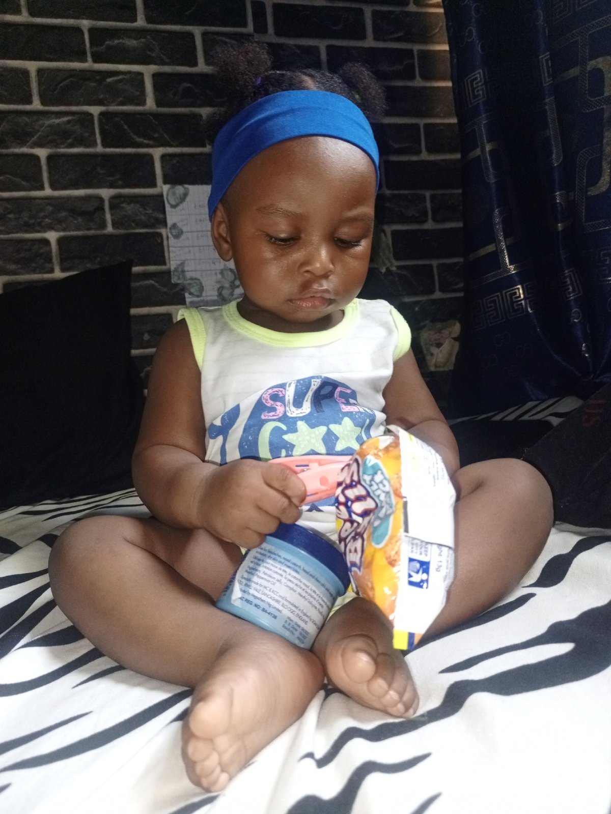 Young child observed playing with teething toy on bed