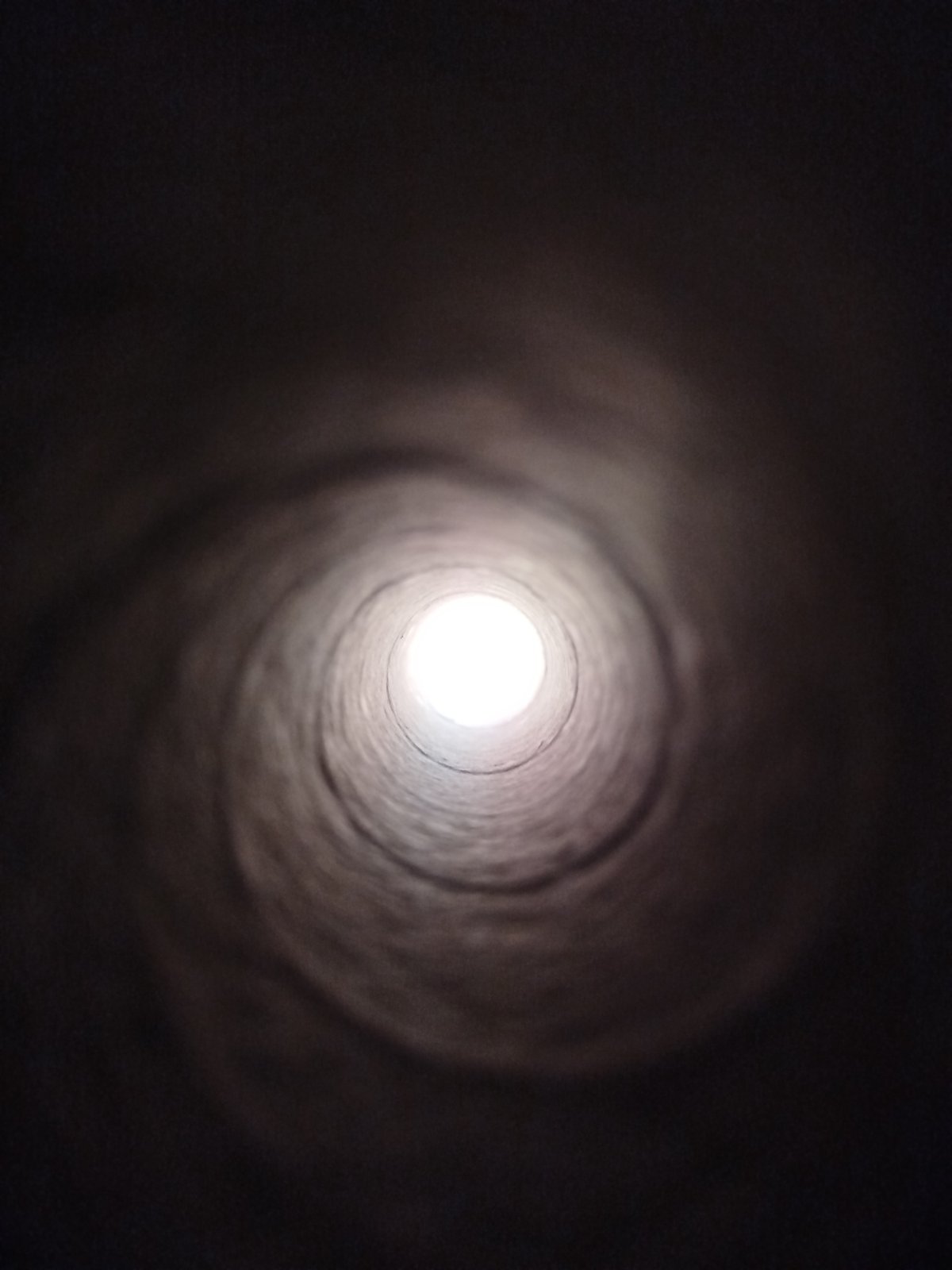 Inside a dark concrete tunnel, light at the end