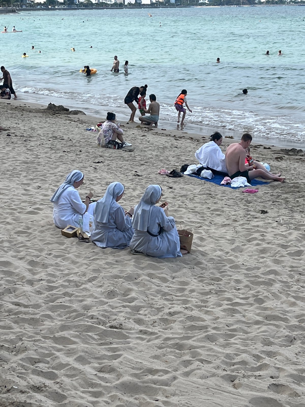 Beach gathering includes swimmers, couples, nuns in Bắc Nha Trang