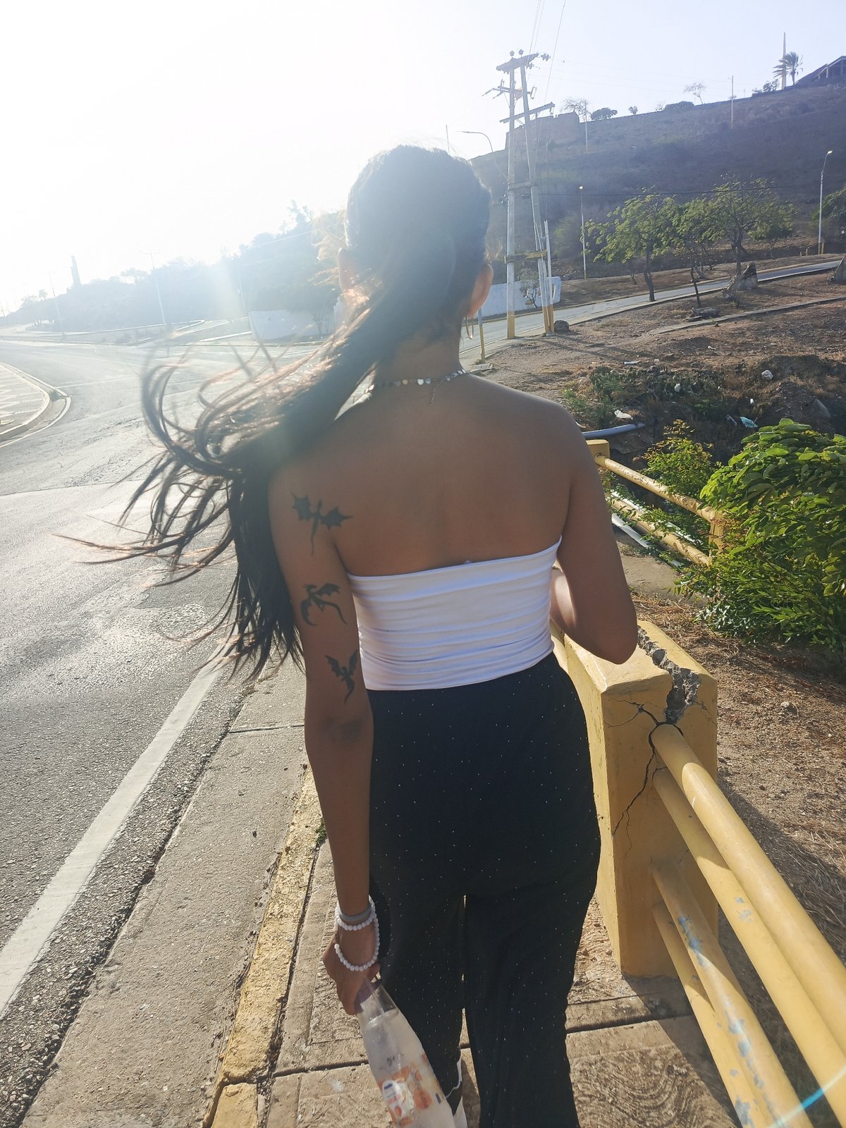 Woman walks coastal road in Juan Griego during sunny evening