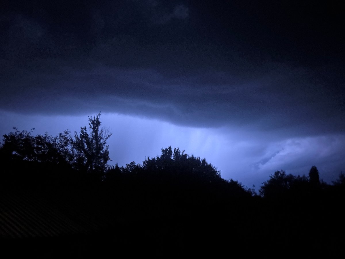 Electric blue-purple light illuminates storm clouds at night