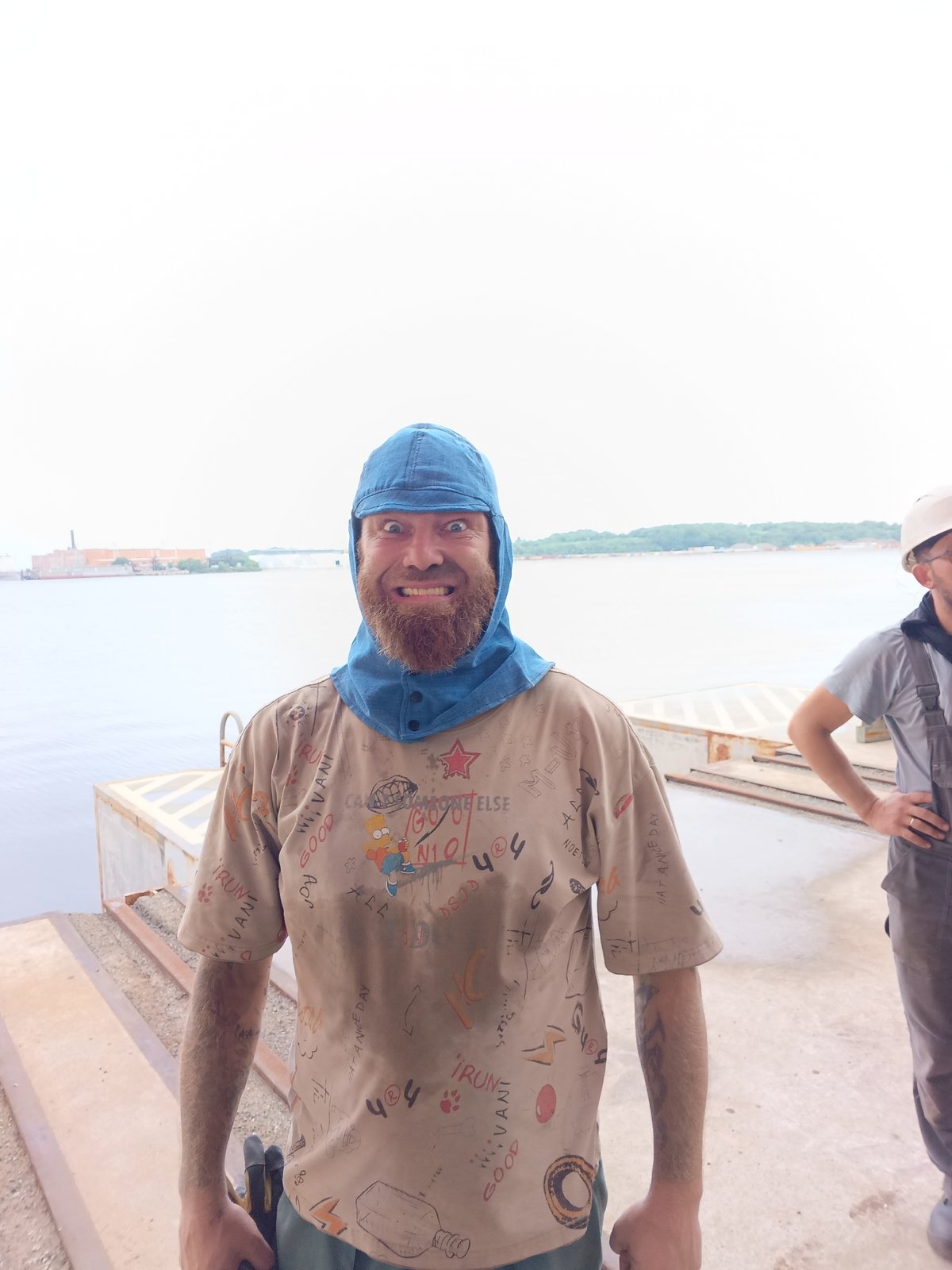 Two people hanging out on a waterfront dock, one filming.