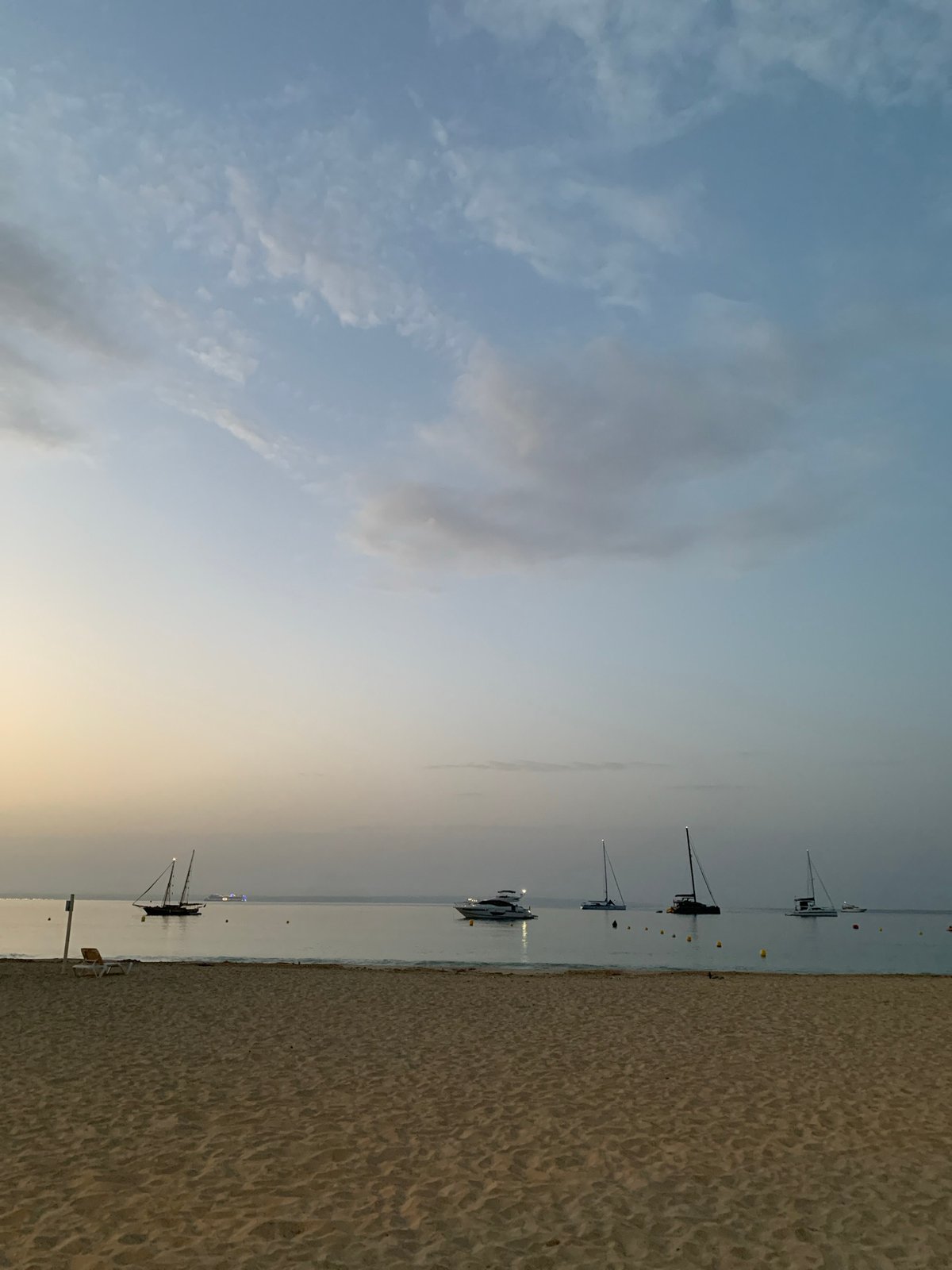 Palmanova beach at golden hour, boats anchored, shore at rest
