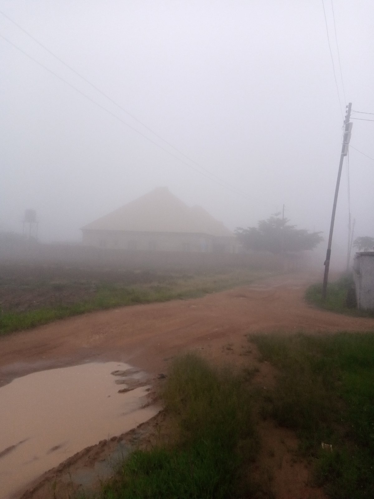Foggy rural morning: dirt roads, a motorcycle, and a market stall