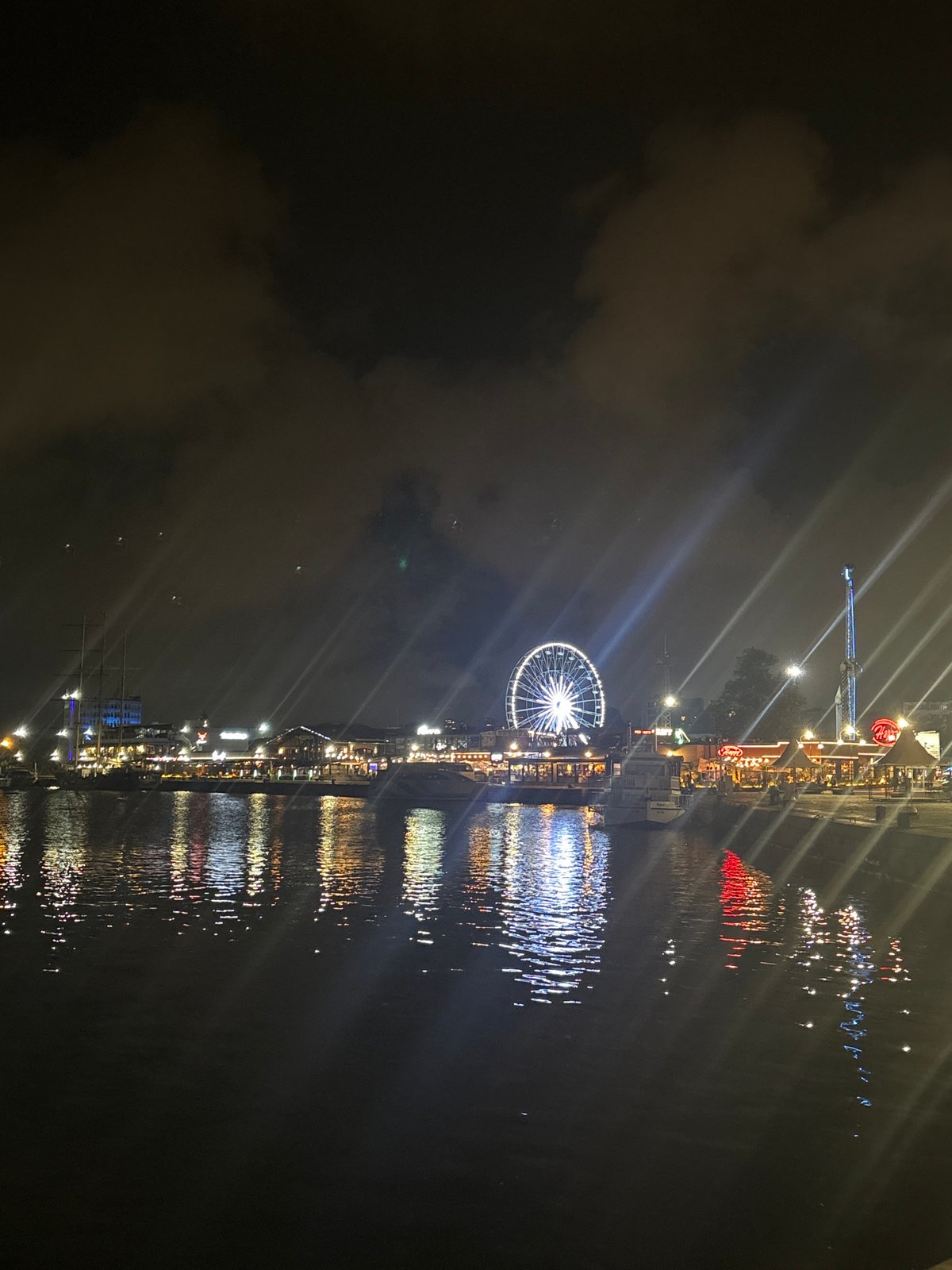 Waterfront entertainment district documented with Ferris wheel, dining venues