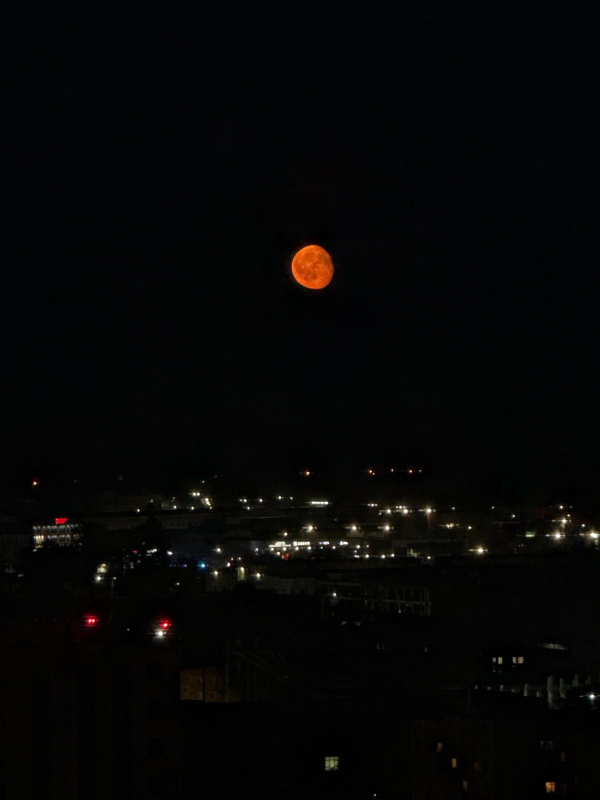 Orange full moon rises over Perm city at night