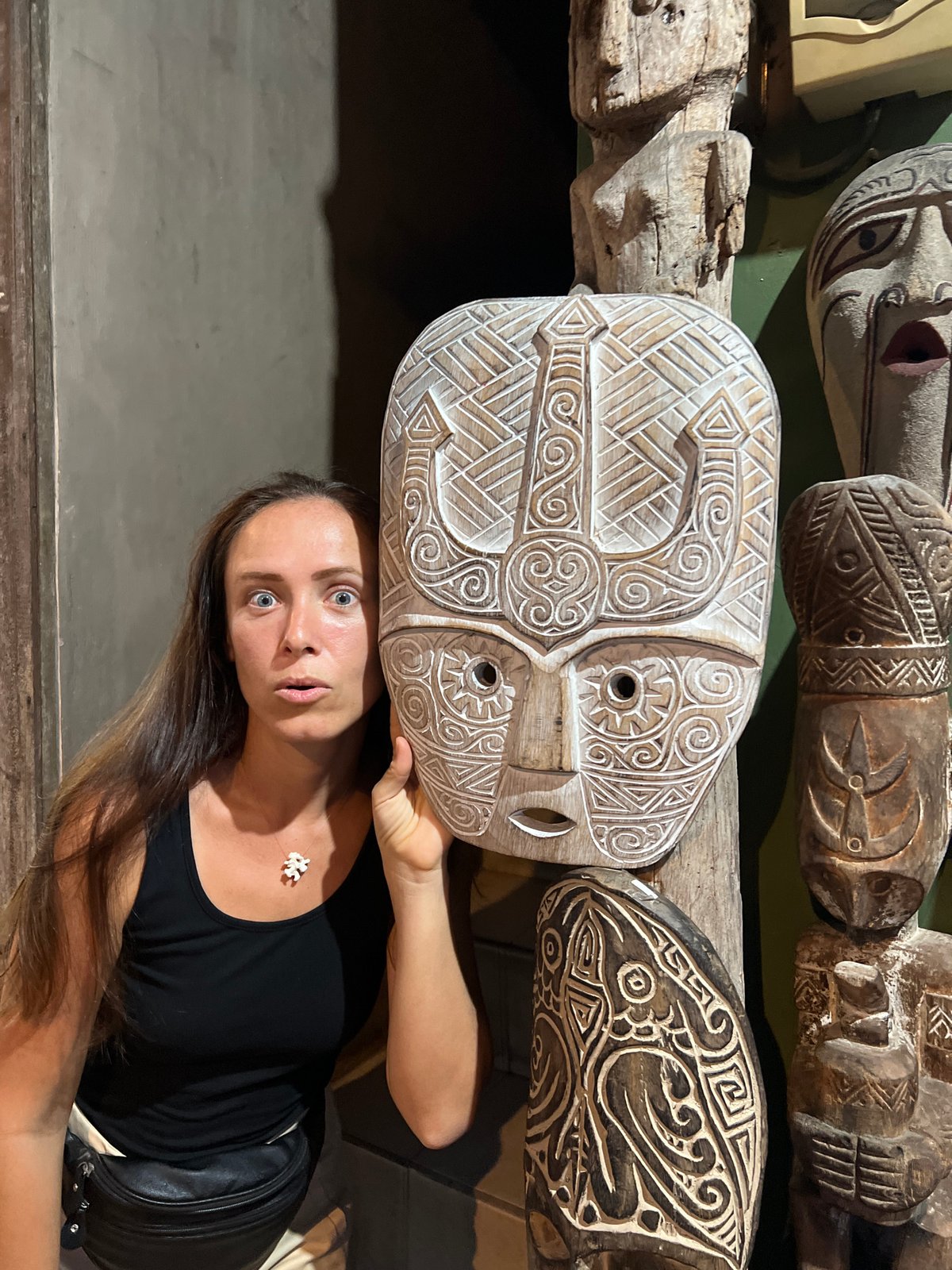 Tourist examines traditional carved masks at Ubud craft display