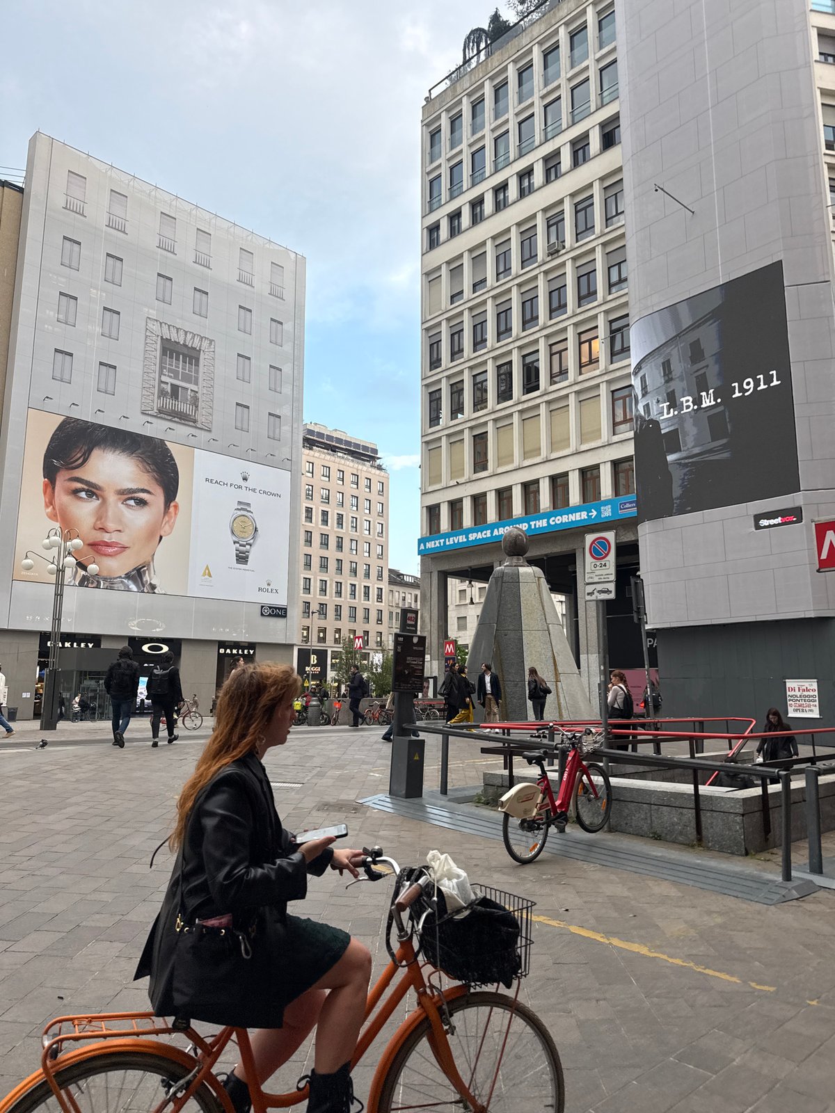 Woman uses phone while on bicycle in Milan street