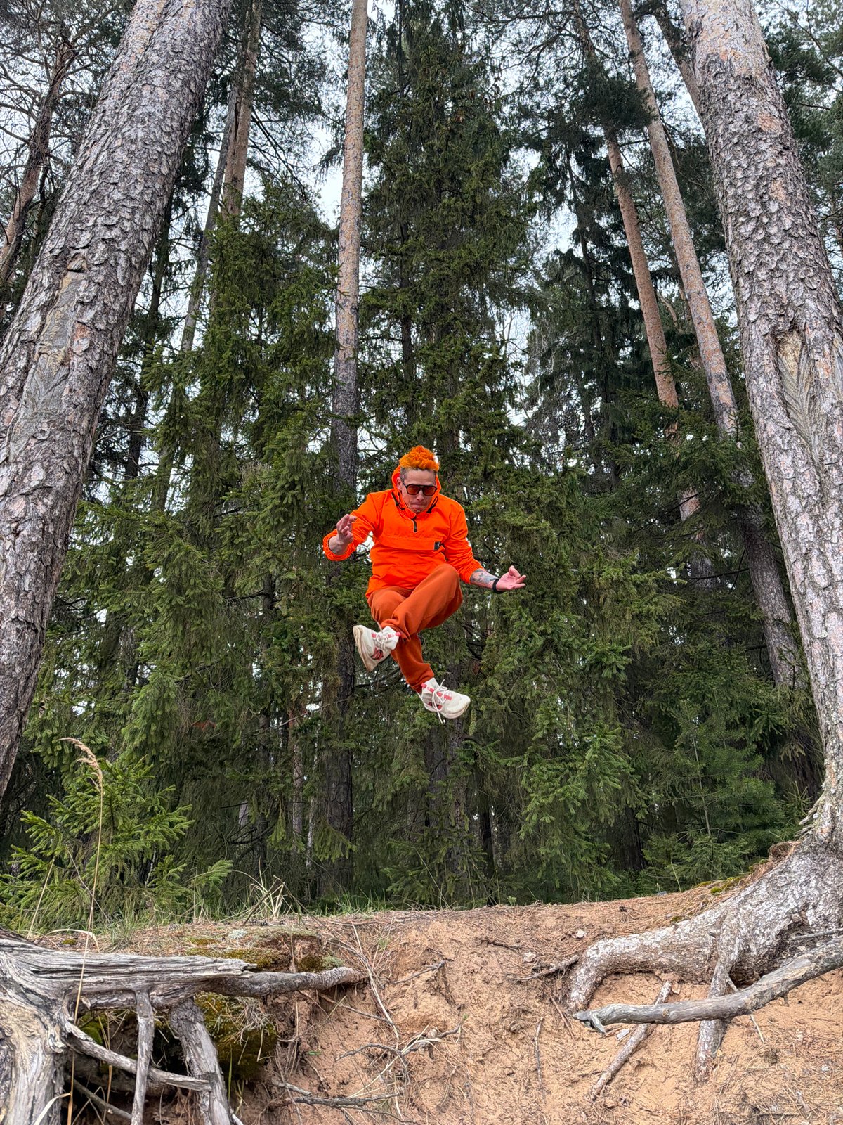 Person in orange performs acrobatics in Russian forest