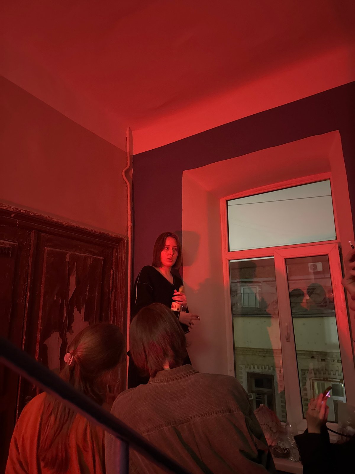 Social gathering documented in red-lit Moscow interior during evening hours