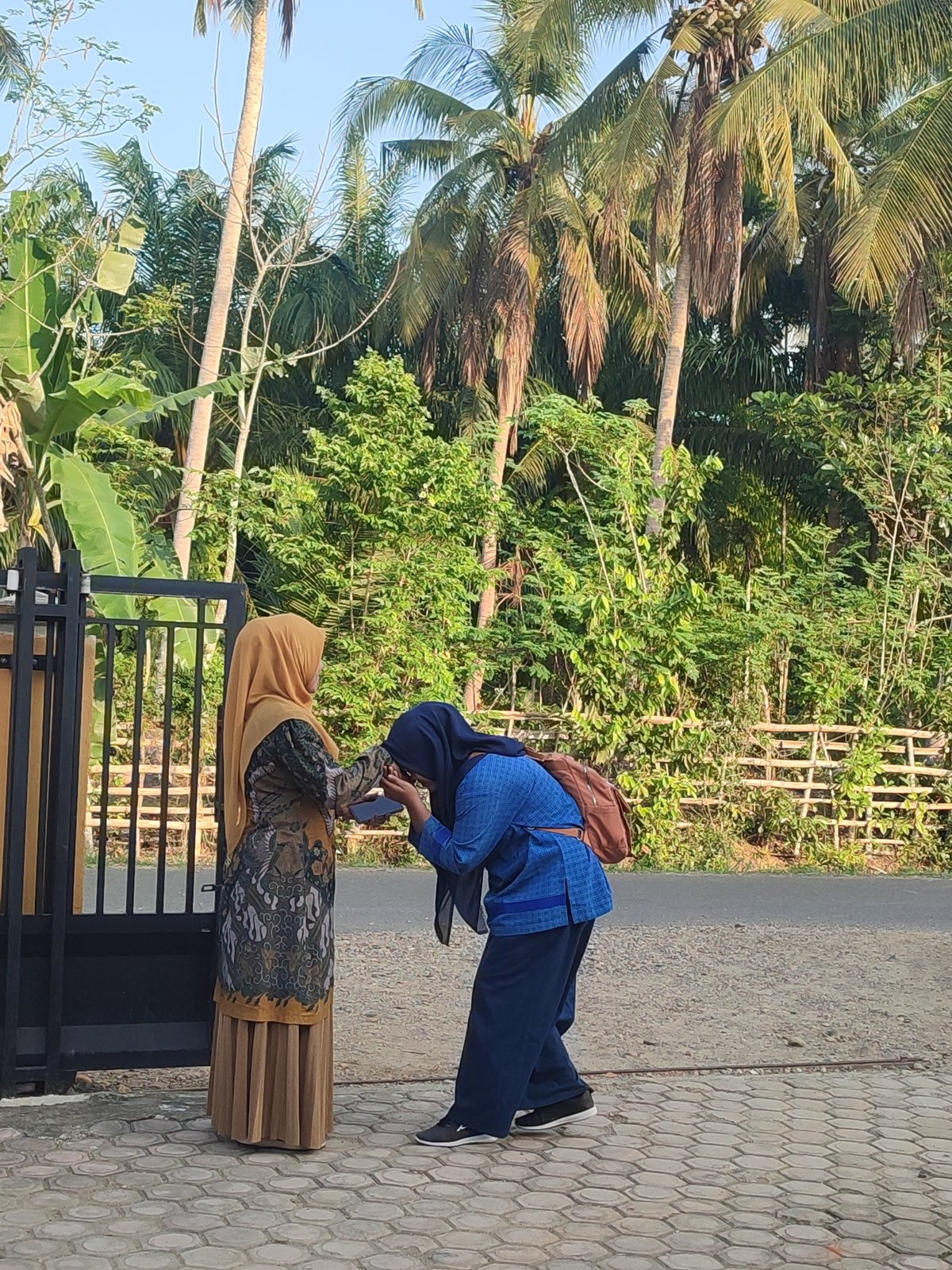 Two women photographed near gate in Blangriek, Indonesia