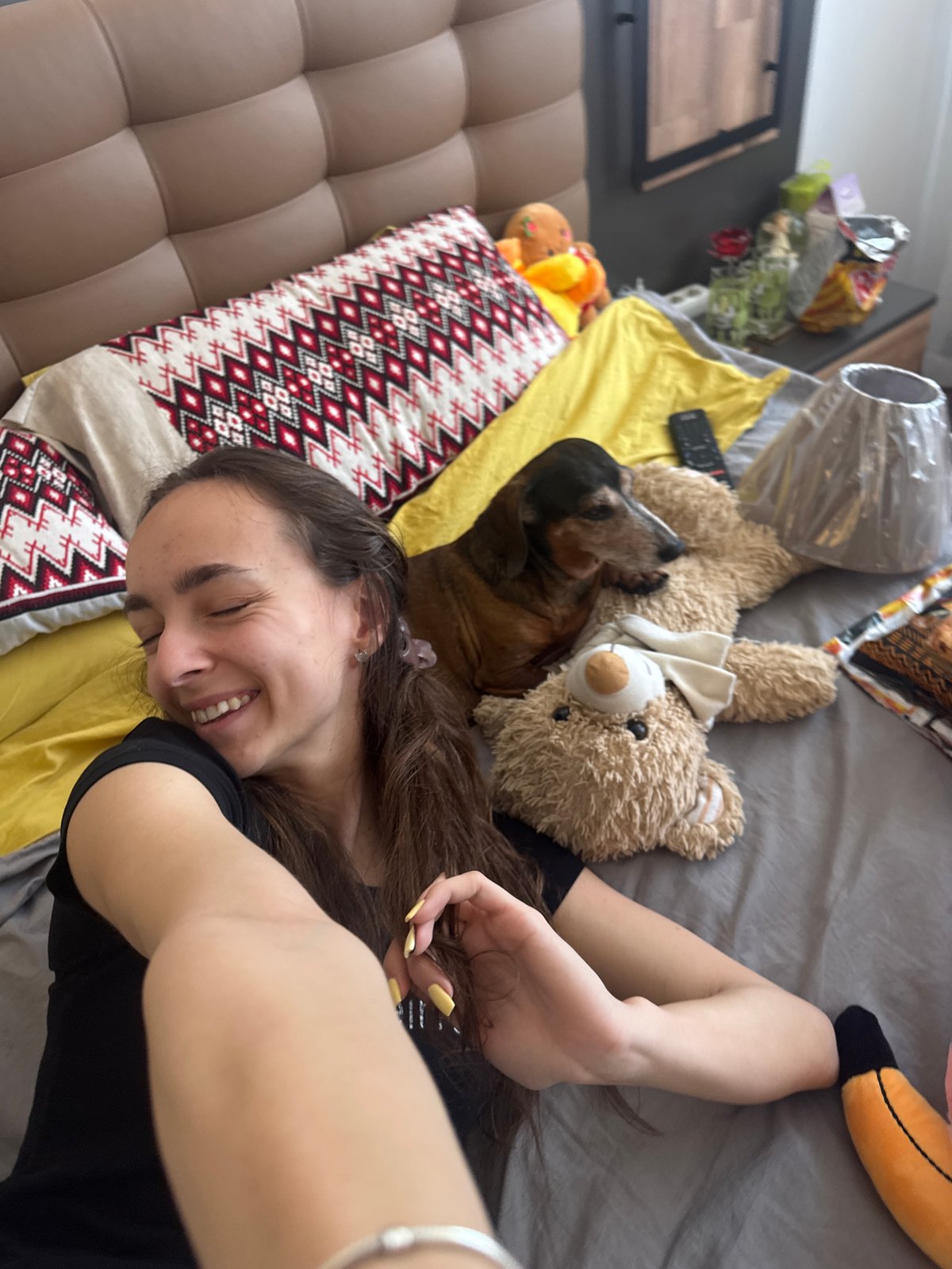 Woman enjoys morning bedroom time with dog and toys