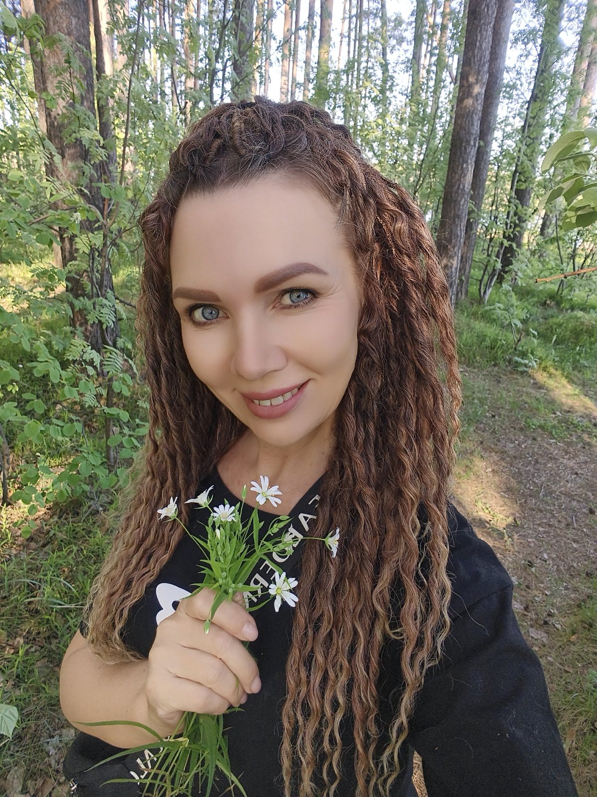 Woman photographed with white flowers in wooded lakeside area