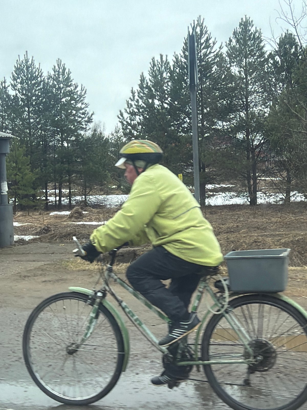 Cyclist rides muddy forest path amid snow patches in Russia