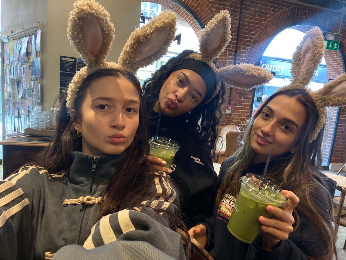 Three women in bunny ears pose with green drinks