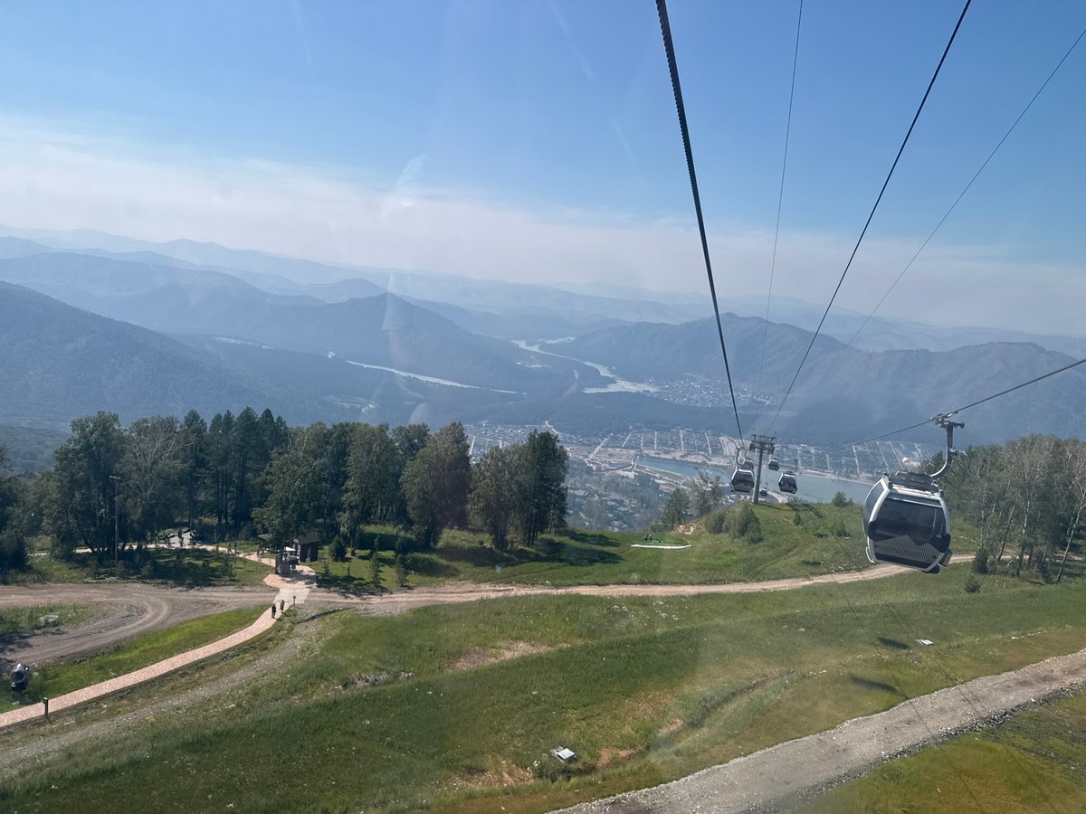 Cable car descending a green mountain slope in Ozernoe, Russia.