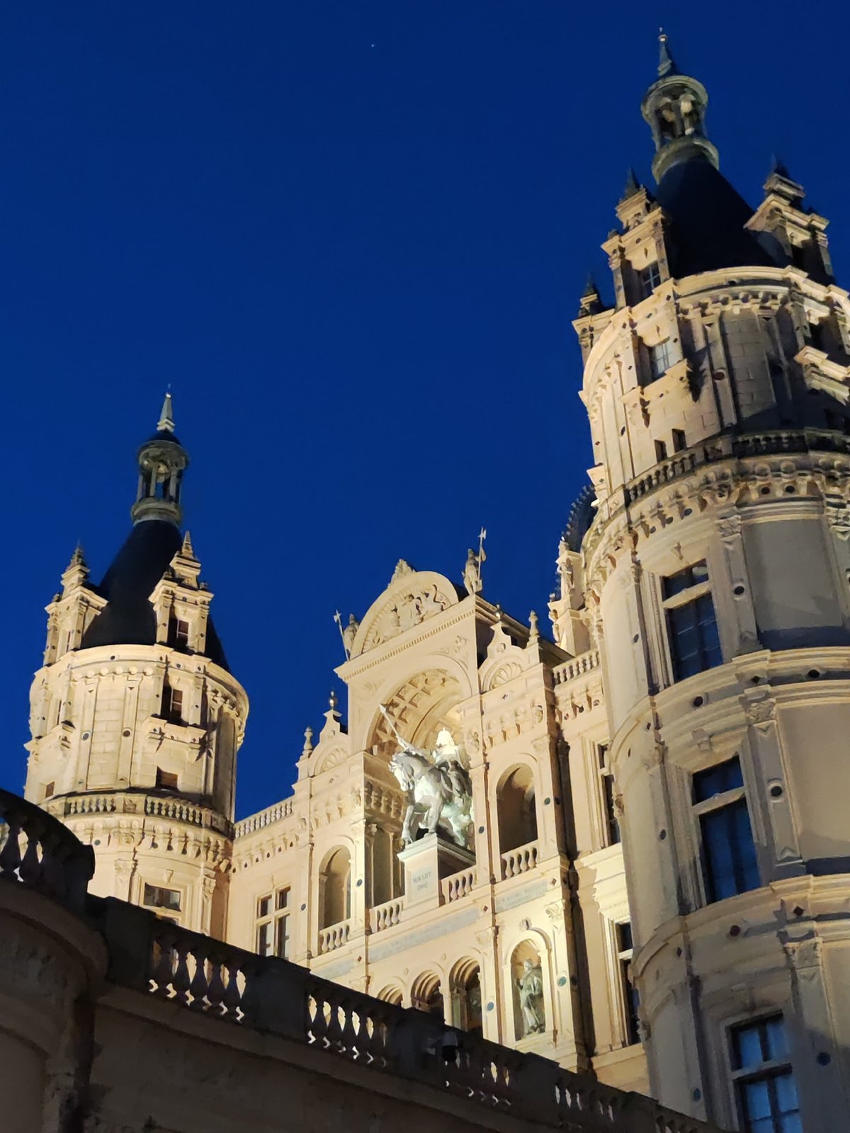 Schwerin Castle glowing after dark, lake reflections included