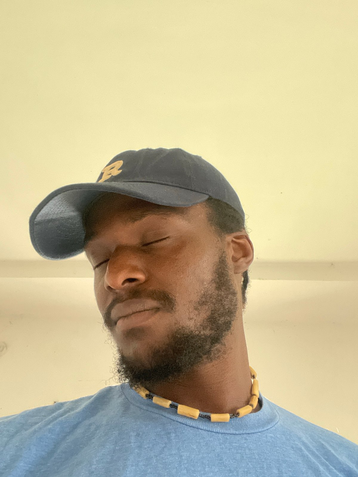 Quiet close-up portrait in Abuja, eyes closed, beaded necklace