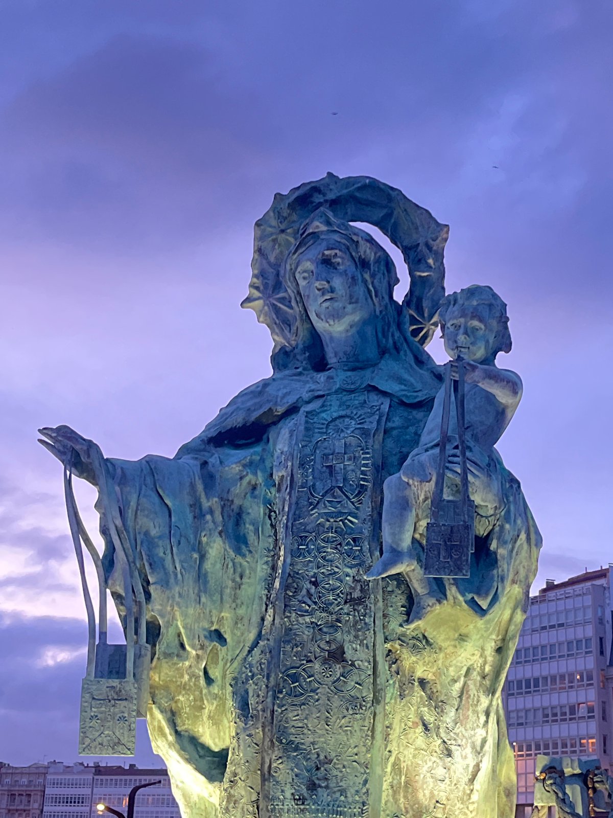 Historic bronze monuments photographed at dusk in A Coruña