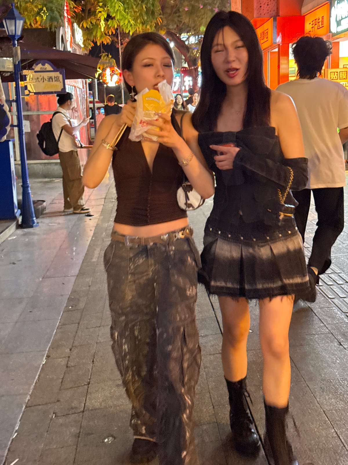 Young women socialize on busy Liangjiang streets during evening hours