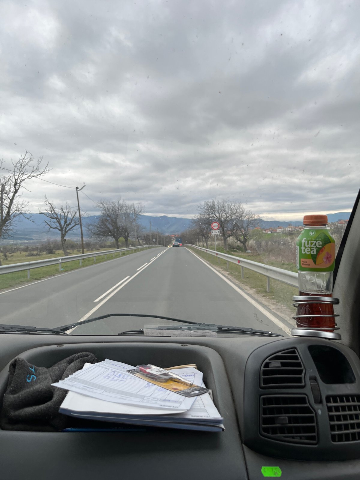 Vehicle travels countryside road near Anevo, Bulgaria under overcast skies