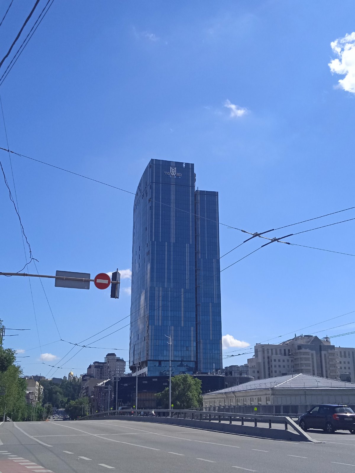 Blue glass skyscraper towers over a city street corner